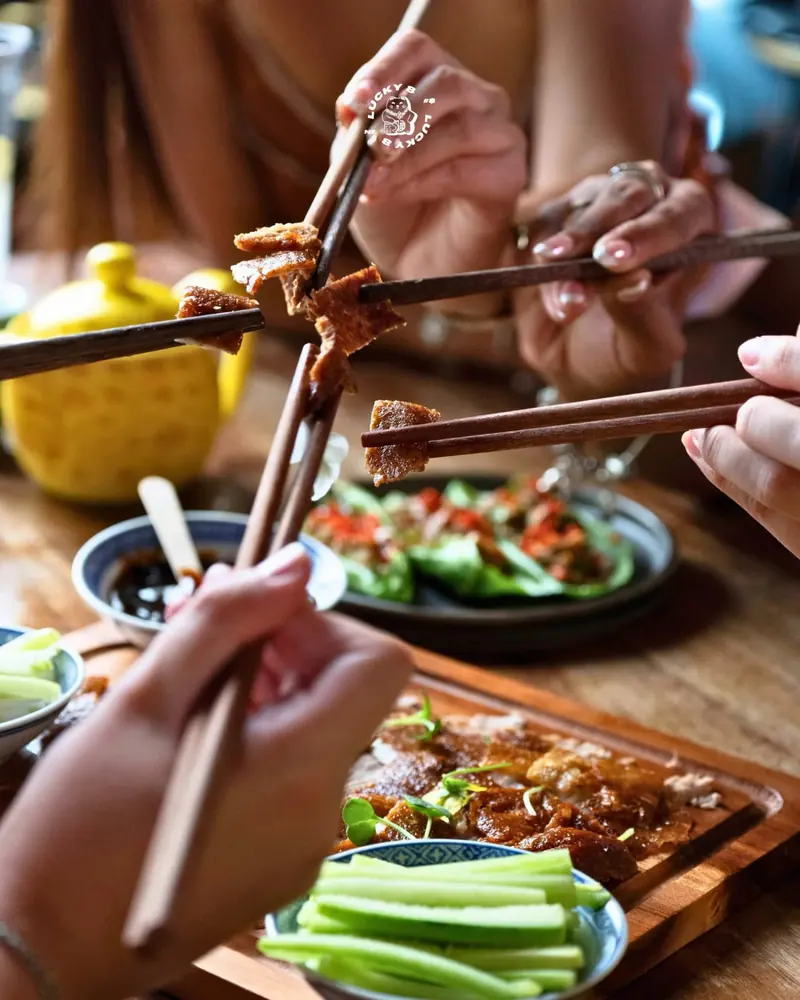 Chopsticks sharing crispy pork across the table